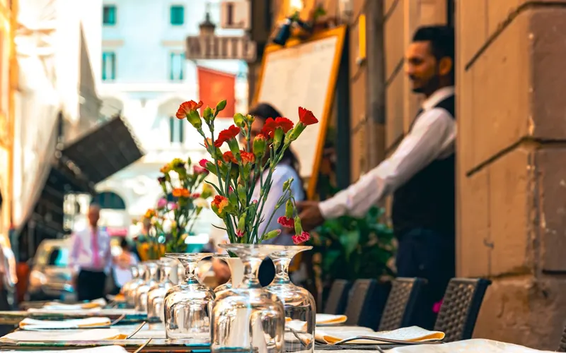 Waiter serving a set table at an outdoor restaurant terrace