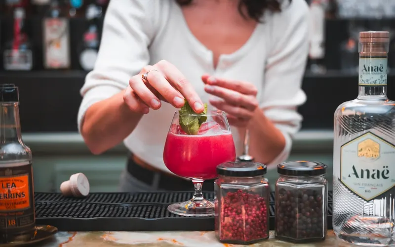 Bartender garnishing a cocktail behind the bar
