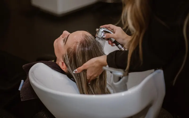 Stylist washing a client’s hair at a salon basin