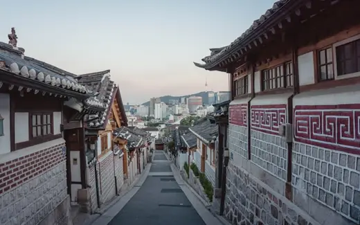 A hanok alley in Bukchon, Seoul, with the city behind